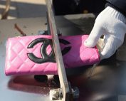 cutting fake pink chanel wallet to illustrate the need to remove counterfeit