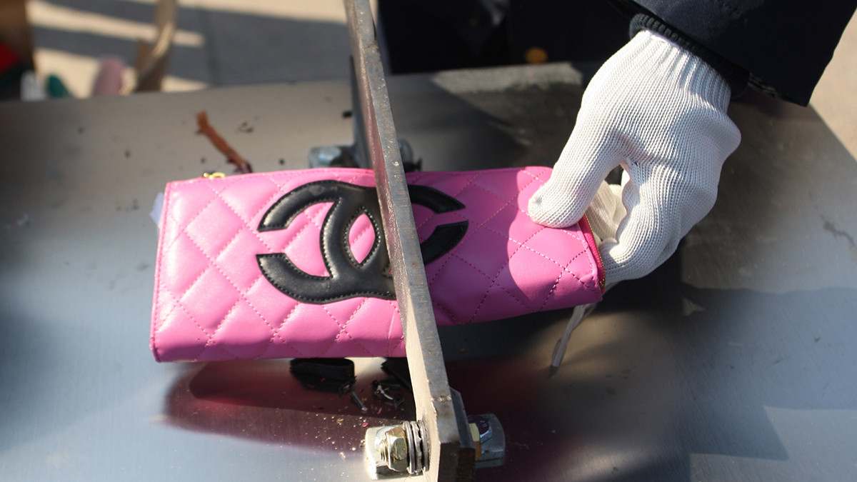 cutting fake pink chanel wallet to illustrate the need to remove counterfeit